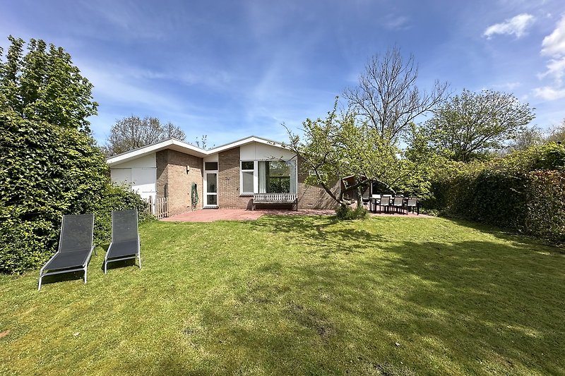 Ländliches Haus mit grünem Garten und blauem Himmel.