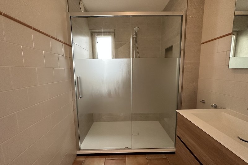Modernes Badezimmer mit Glasdusche, Holzdetails und Aluminiumarmaturen.