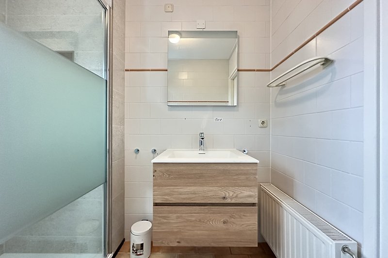 Badezimmer mit Spiegel, Waschbecken und Holzdetails.