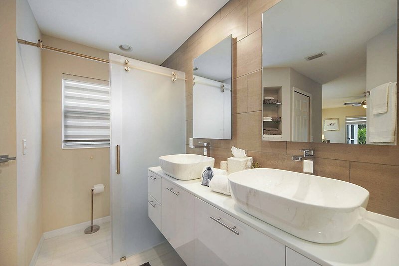 Ein modernes Badezimmer mit Spiegel, Waschbecken und Armaturen.