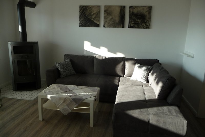 Gemütliches Wohnzimmer mit bequemer Couch, Holztisch und grauem Interieur.