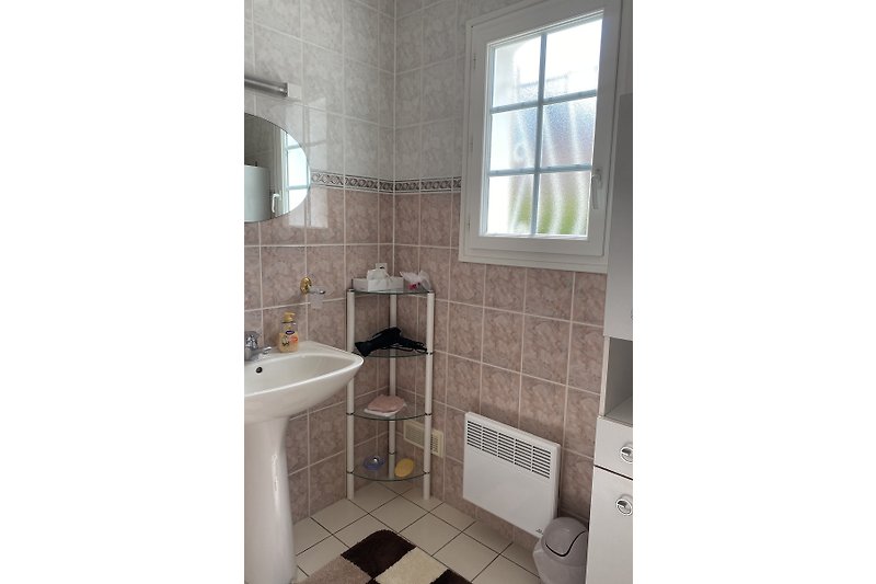 Badezimmer mit Dusche, Spiegel, Fenster, Waschbecken und Schränkchen