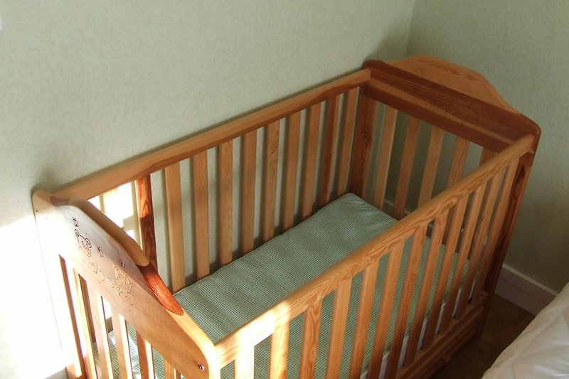 Babyzimmer mit Holzmöbeln, Spielzeug und bequemem Bett.