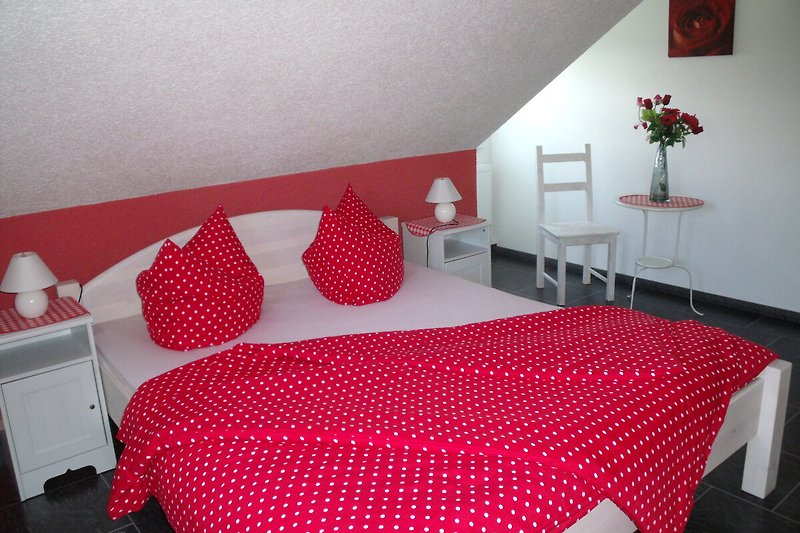 Gemütliches Schlafzimmer mit rotem Bett, Pflanzen und stilvoller Dekoration.