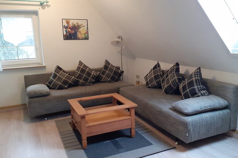Wohnzimmer mit bequemer Couch, Tisch, Lampe und Bilderrahmen. Gemütliche Atmosphäre.