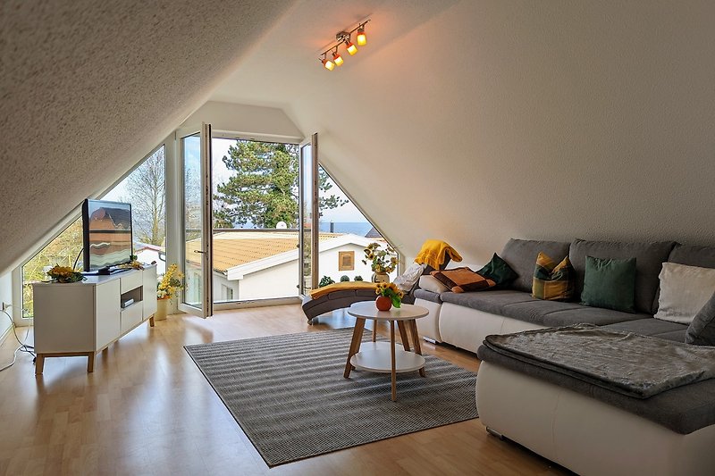 Wohnbereich mit Sofa, Sat-TV, Relax-Sessel, großer Fensterfront mit Meerblick
