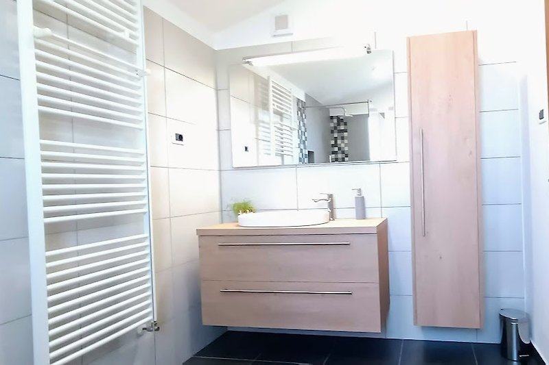 Moderan i čist kupaonski prostor s ogledalom, slavinom i umivaonikom.