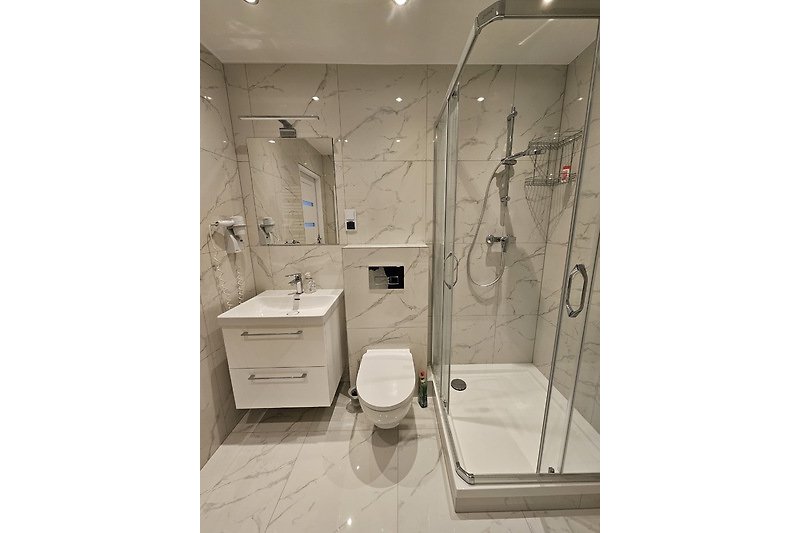 Modernes Badezimmer mit Dusche, Waschbecken und Glasduschtür.