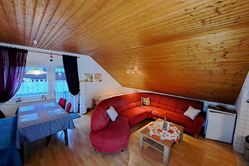 Gemütliches Wohnzimmer mit Holzmöbeln und bequemer Couch. Balkon mit Morgensonne