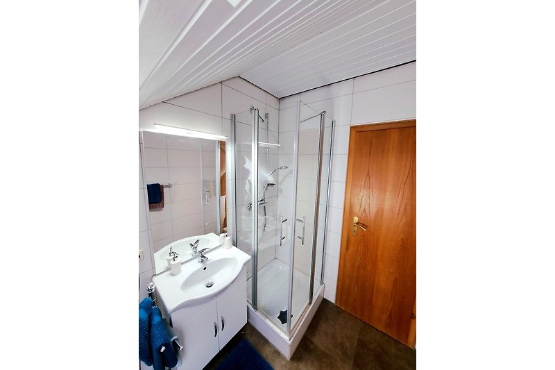 Gemütliches Badezimmer mit Spiegel, Waschbecken und Dusche.