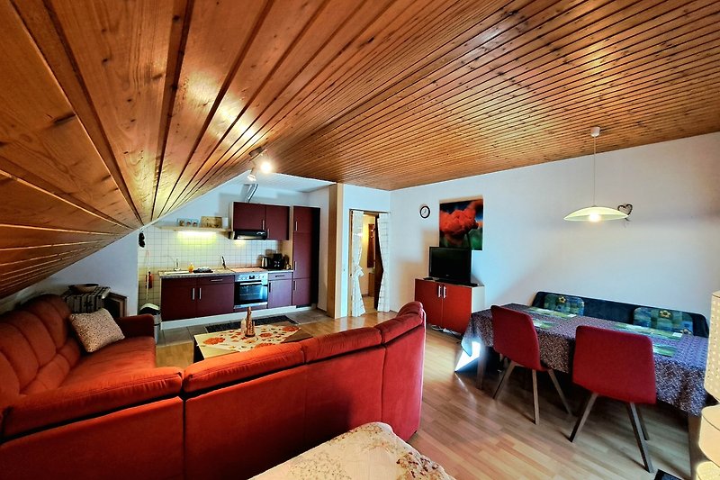 Gemütliches Wohnzimmer mit Holzmöbeln, bequemer Couch, TV, Esstisch, Fussbodenheizung