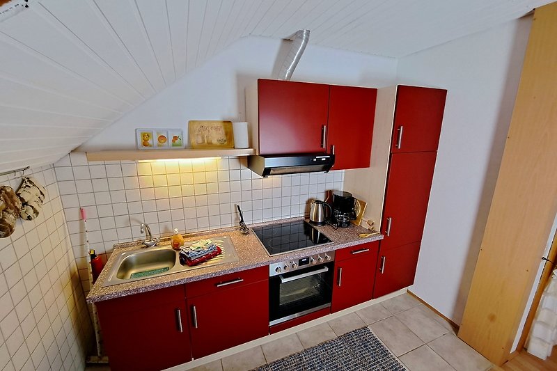 Moderne Küche mit Holzschränken, Spüle, Cerankochplatten, Backofen, Kaffeemaschine, Wasserkocher, Kühlschrank
