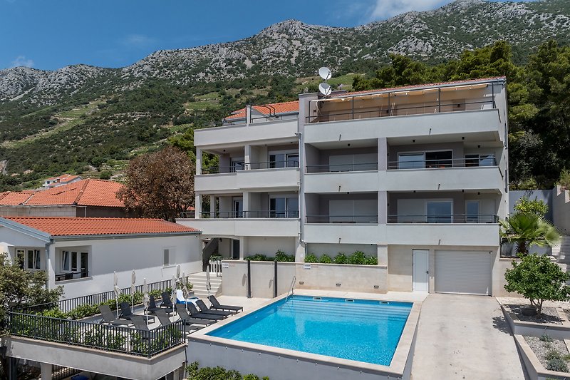 Moderne Villa mit Pool und Bergblick, umgeben von Palmen.