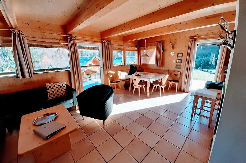 Gemütliches Wohnzimmer mit Holzmöbeln und Blick auf den See.