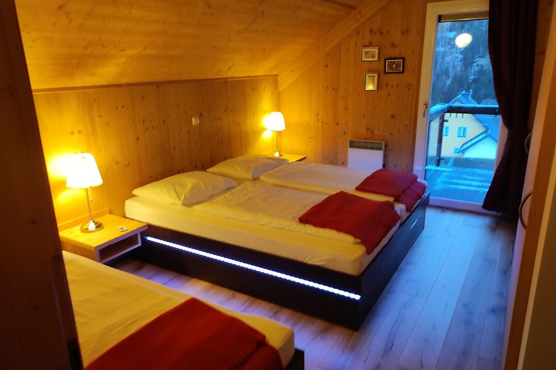 Gemütliches Schlafzimmer mit Holzbett, Lampen und Vorhängen.