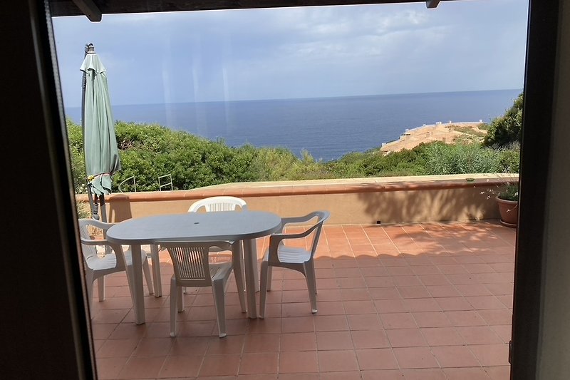 Eine grosszügige  Terrasse mit Möbeln und Blick auf  das Meer.