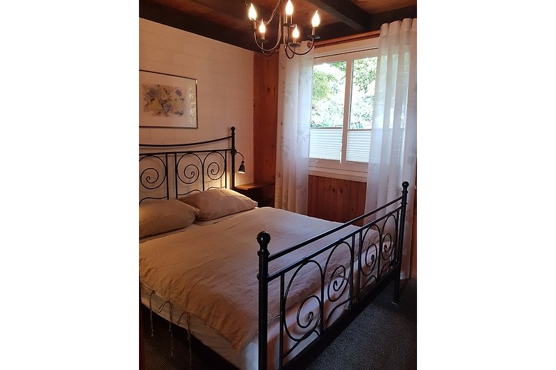 Gemütliches Schlafzimmer mit Holzbett und stilvoller Beleuchtung.