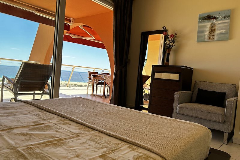 Schlafzimmer mit Doppelbett und direktem Zugang zur Terrasse, direkter Meerblick vom Bett