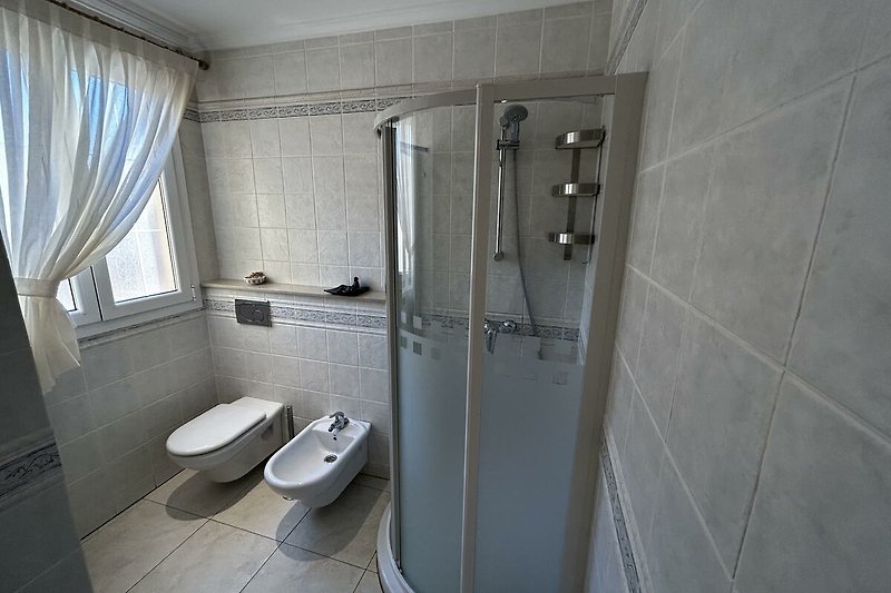 Modernes Badezimmer mit stilvollem Design, Dusche, Waschbecken und Fenster.