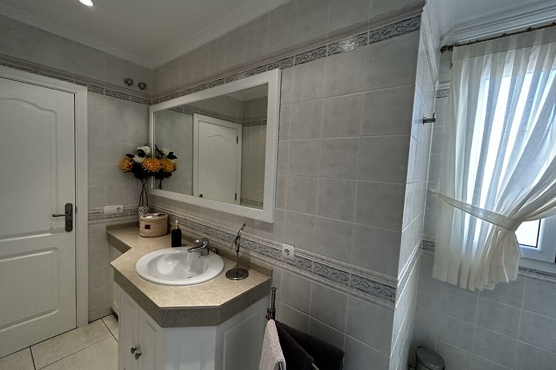 Modernes Badezimmer mit stilvollem Design, Spiegel, Waschbecken und Badmöbeln.
