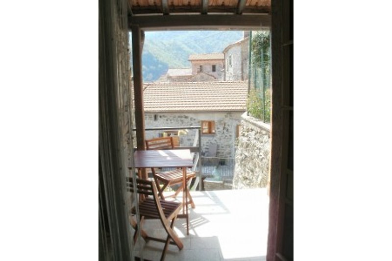 Pogled iz kuhinje na natkriveno sjedeće mjesto na otvorenom i krovni krajolik Villecchie.