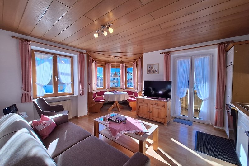 Gemütliches Wohnzimmer mit lila Couch, Fernseher und Holzmöbeln.
