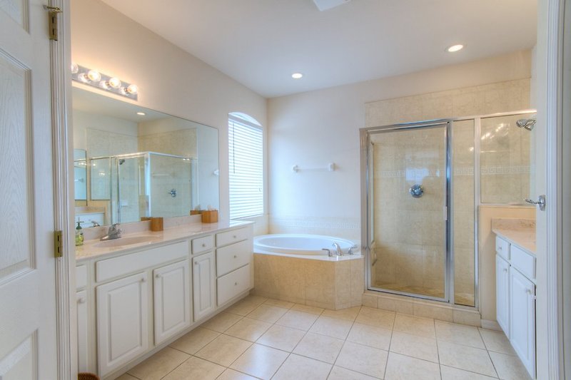Łazienka główna z podwójnym umywalkami, prysznicem, wanną narożną i toaletą.