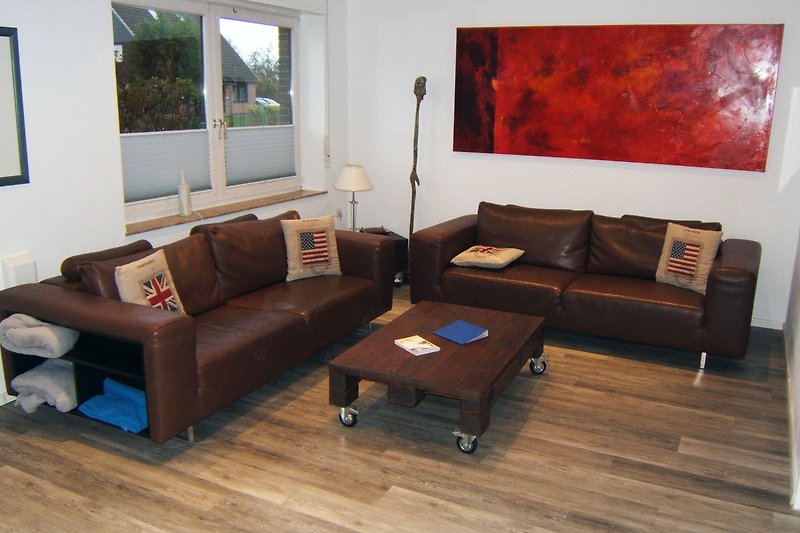 Gemütliches Wohnzimmer mit Holzboden, bequemer Couch und Tisch.