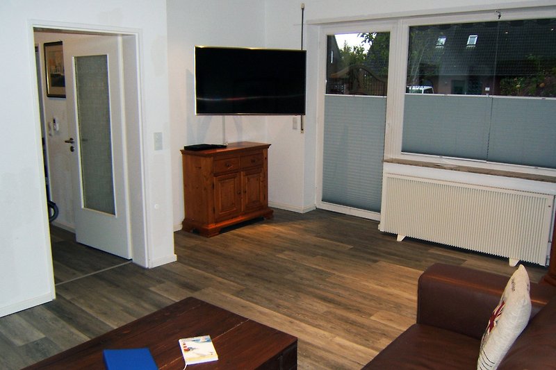 Gemütliches Wohnzimmer mit Holzboden und moderner Einrichtung.