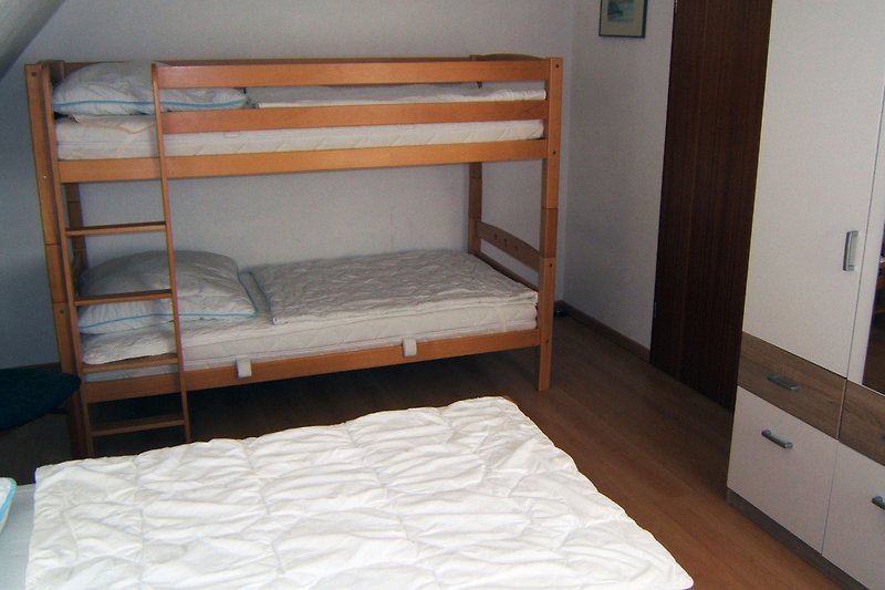 Gemütliches Schlafzimmer mit Etagenbett, Holzmöbeln und gemütlicher Einrichtung.