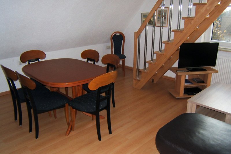 Gemütlicher Innenraum mit Holzmöbeln, Tisch und Stühlen.