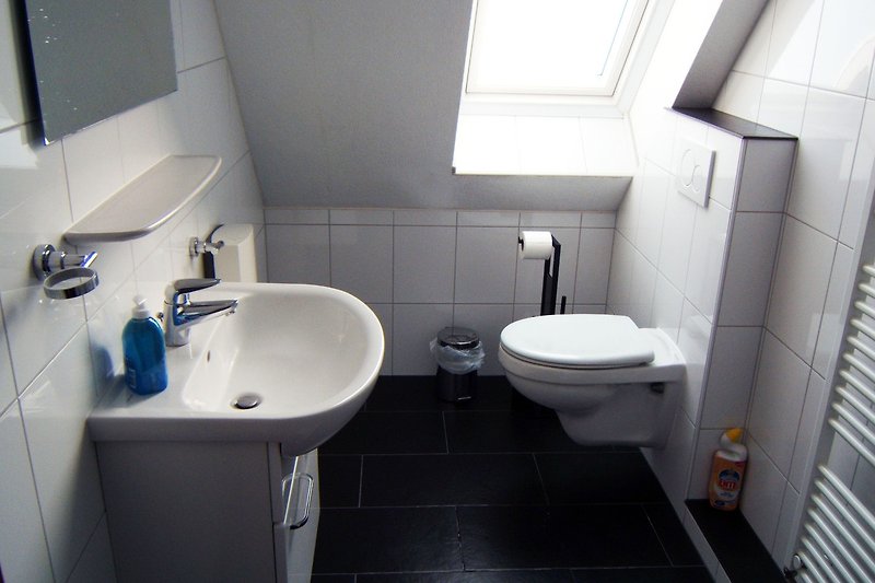 Modernes Badezimmer mit lila Akzenten, Holzboden und stilvollem Waschbecken.