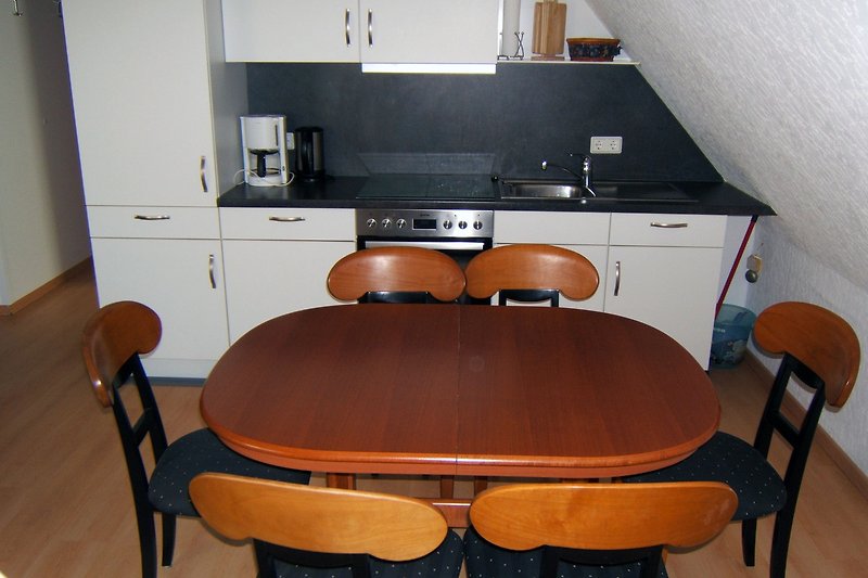 Gemütliches Holzinterieur mit Tisch, Stühlen und Schrank.