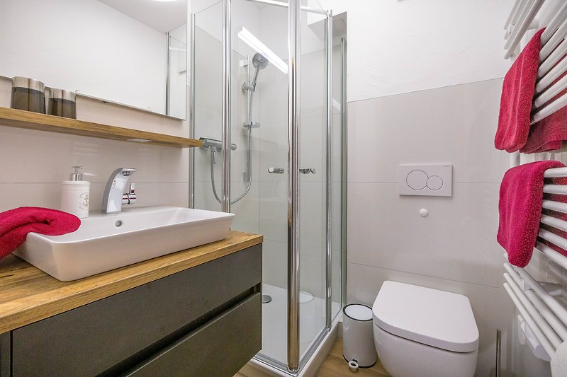 Badezimmer mit lila Akzenten, Spiegel, Waschbecken und Dusche.