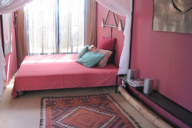 Cosy sleeping room in red tones with double bed  and mosquito net around and air condition.
Sleep well!