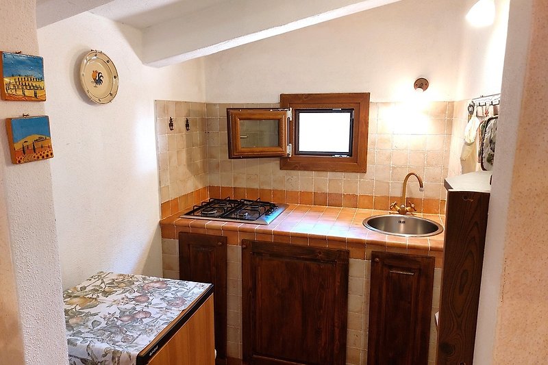 Küche mit Vierflammenherd, Spüle und Fenster.