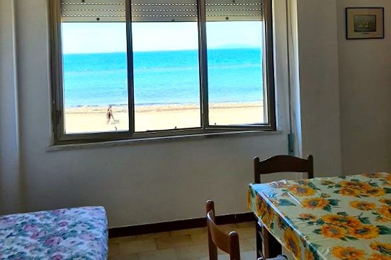 Strandwohnung mit Meerblick, Holzmöbeln, Tisch am Fenster