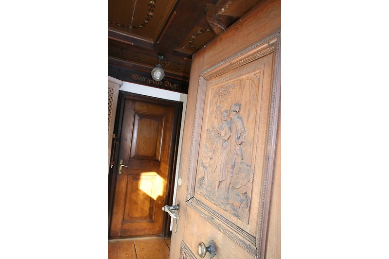 Einladende Holztür mit antikem Griff und kunstvollem Muster