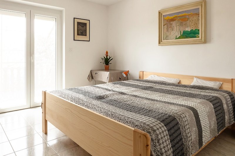 Schlafzimmer mit bequemem Bett, Holzmöbeln und Pflanzen.