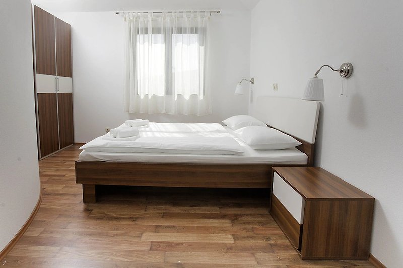 Gemütliches Schlafzimmer mit Holzbett und Fensterbehang.