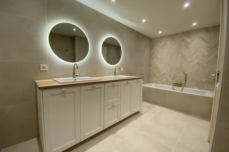 Ein stilvolles Badezimmer mit Spiegel, Waschbecken und Schränken.