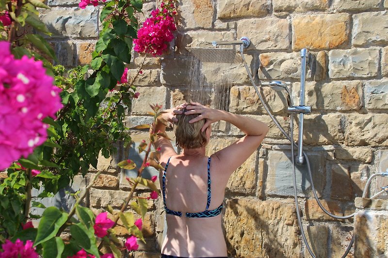 Duschen zwischen Bourgonvillea-Blüten und Oleander als Sichtschutz