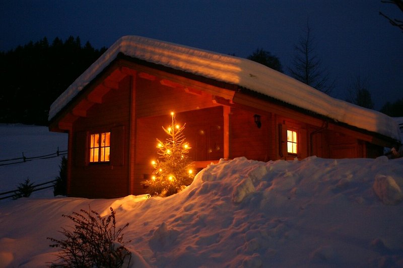 Ein charmantes Holzhaus mit verschneitem Dach und gemütlichem Fensterblick.