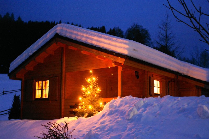 Ein winterliches Holzhaus mit weihnachtlicher Dekoration.