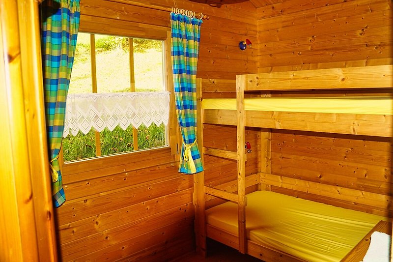 Gemütliches Zimmer mit Holzboden, Fenster und Vorhängen.