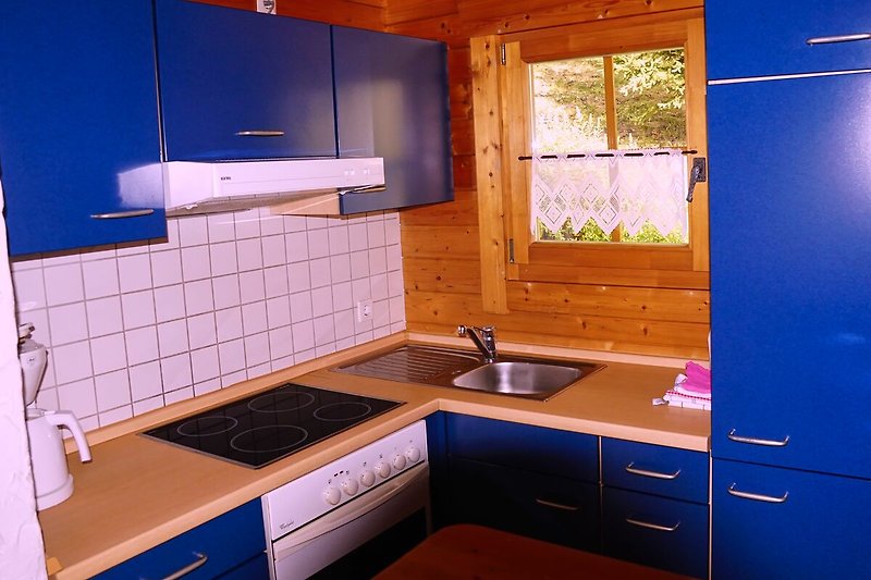 Eine moderne Küche mit lila Schränken, Holzarbeitsplatte und blauer Beleuchtung.