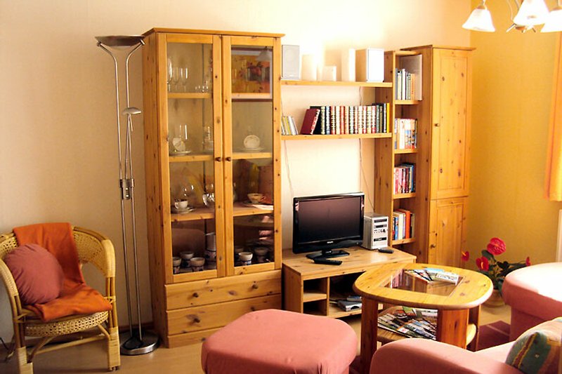 Gemütliches Wohnzimmer mit Holzregalen, bequemen Sesseln, kleiner Bibliothek, Spielesammlung und Stereoanlage.