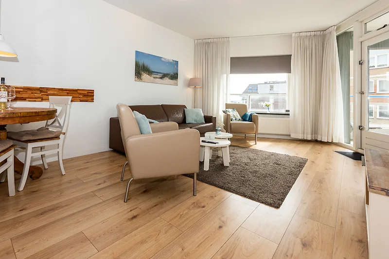 Großes Sofa, Sessel, Couchtisch und Pflanzen im lichtdurchfluteten Loft.