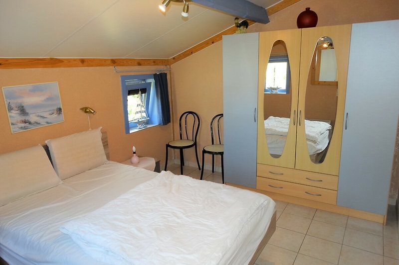 Gemütliches erste Schlafzimmer mit Holzmöbeln, Spiegeln und bequemem Doppelbett (im Erdgeschoss).