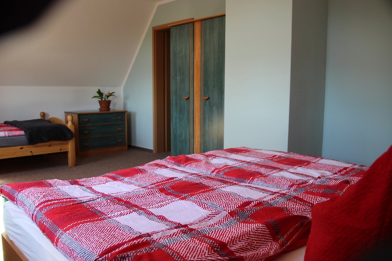 Schlafzimmer mit gemütlichem Doppelbett und einer einzelnen Schlafgelegenheit